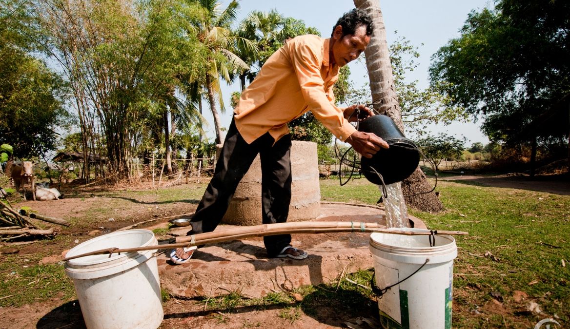 Mann füllt sauberes Wasser in Eimer um - Kambodscha